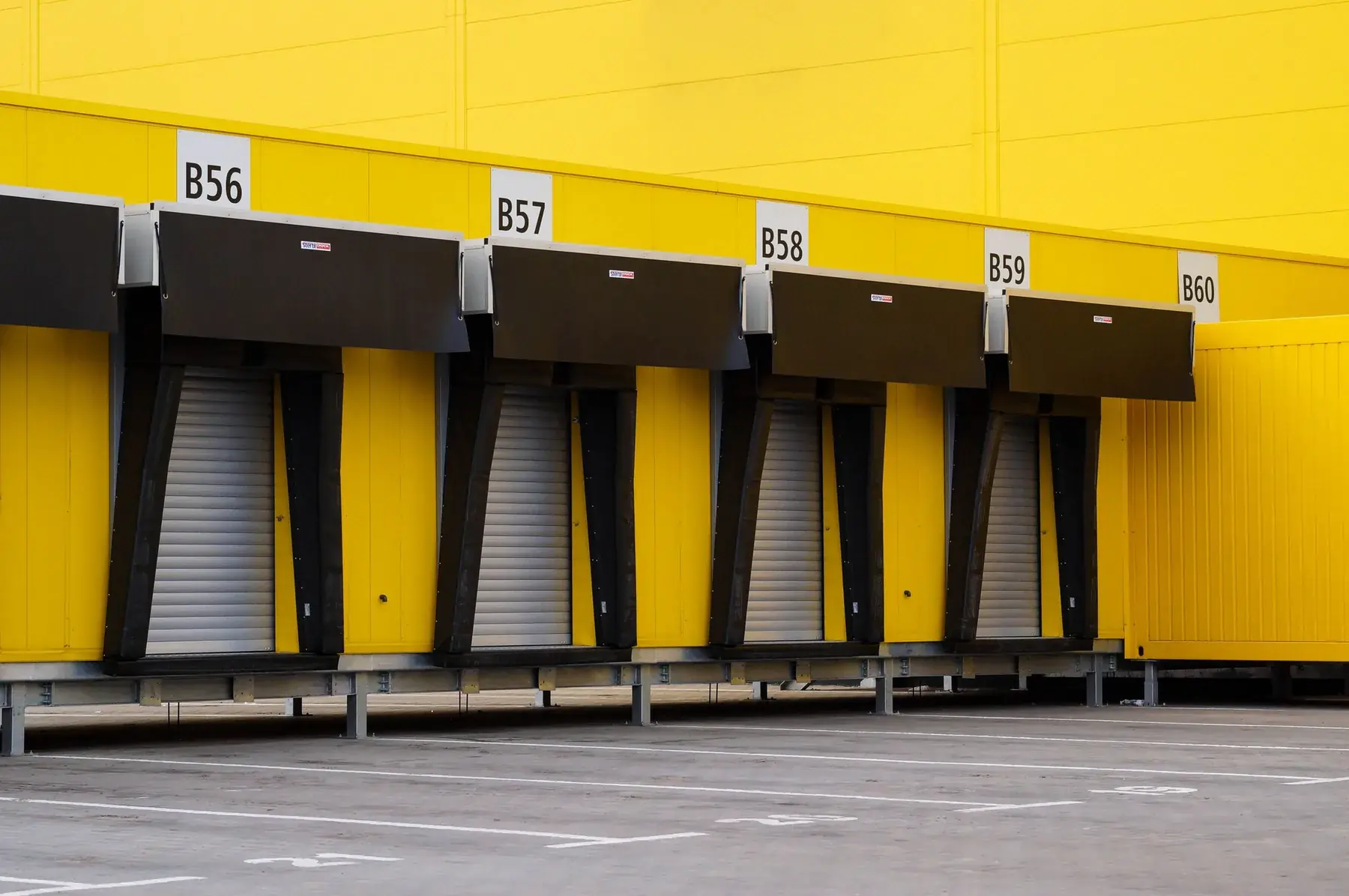 Row of loading dock doors set into a bright yellow warehouse wall