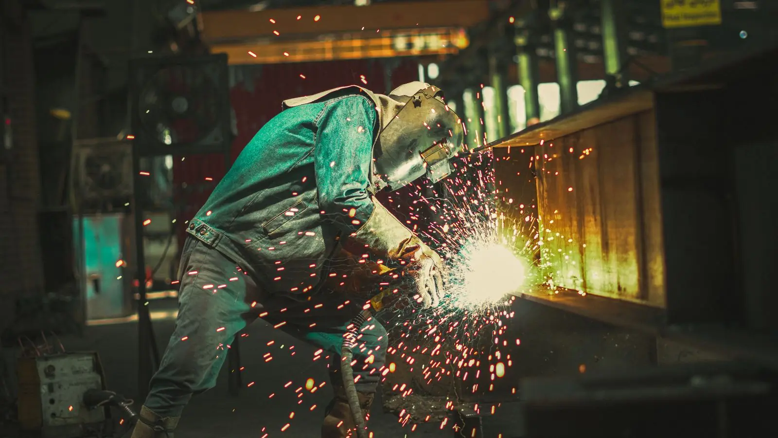 Welder at work in a fabrication shop, with sparks